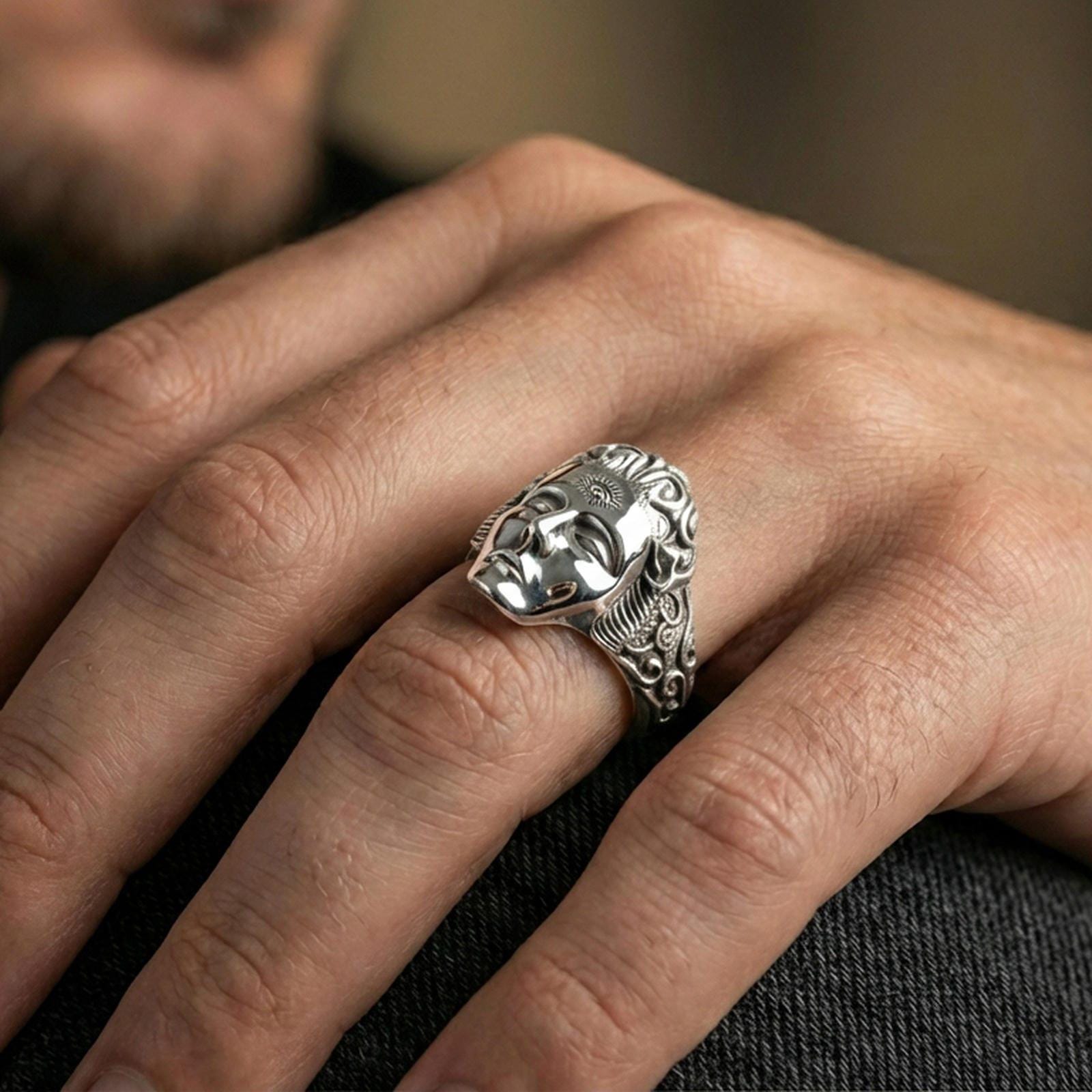 Polished silver finish third eye face ring on the finger, macro lifestyle photo emphasizing the smooth face relief and ornate engraved band