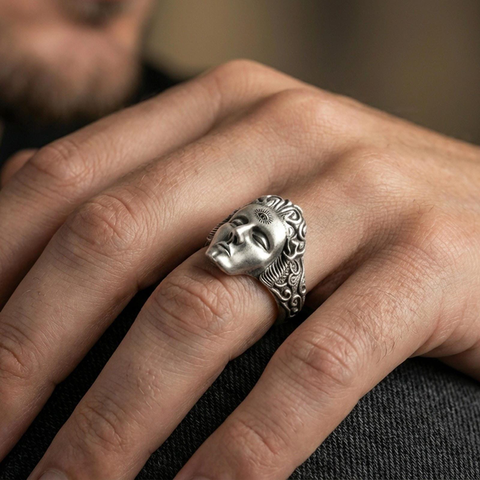 Oxidized finish third eye face ring worn on a finger, close-up lifestyle shot highlighting the sculpted mask and forehead eye symbol