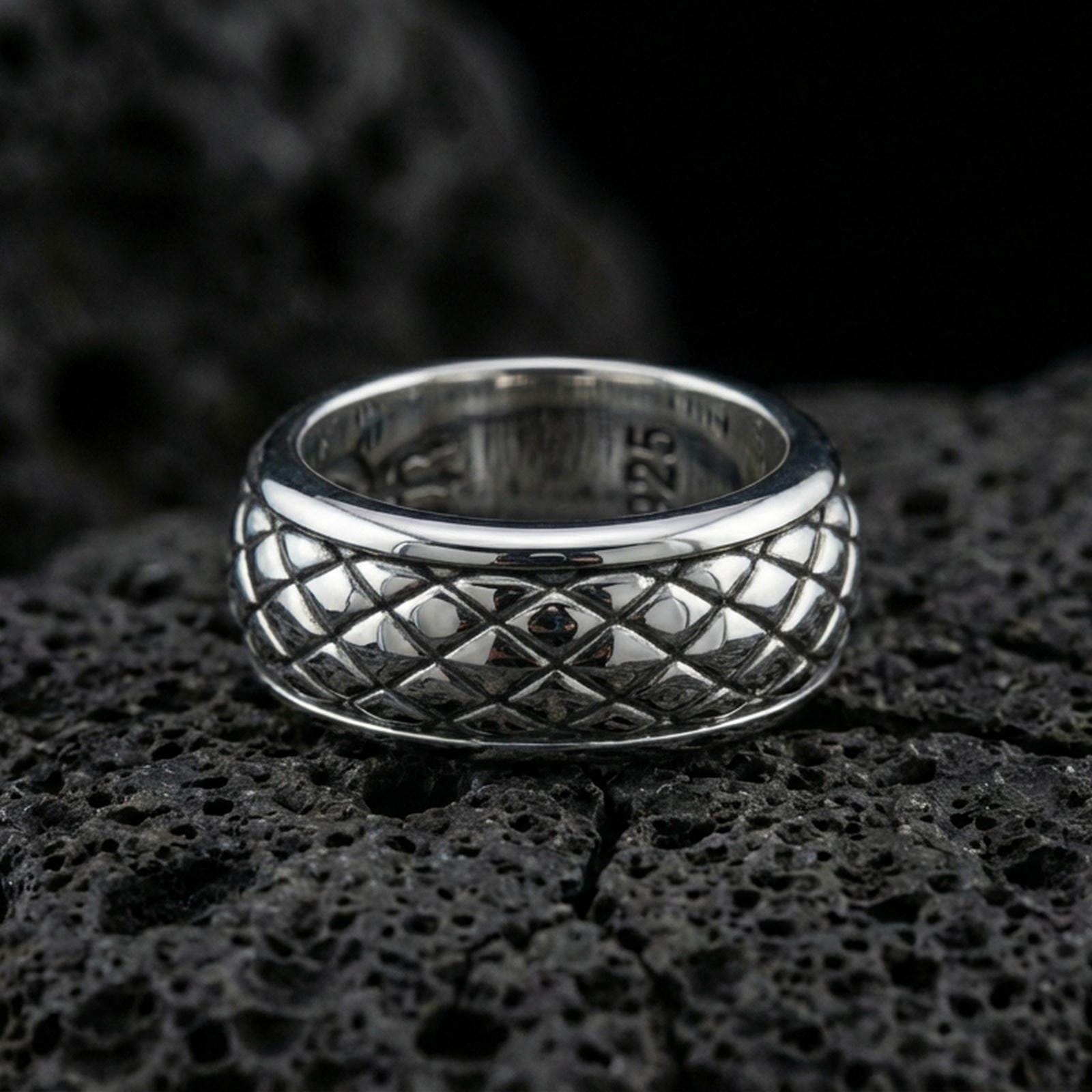 Polished silver diamond quilt texture band ring on black volcanic stone, crisp raised grid pattern with smooth comfort edges, centered close-up studio lighting.