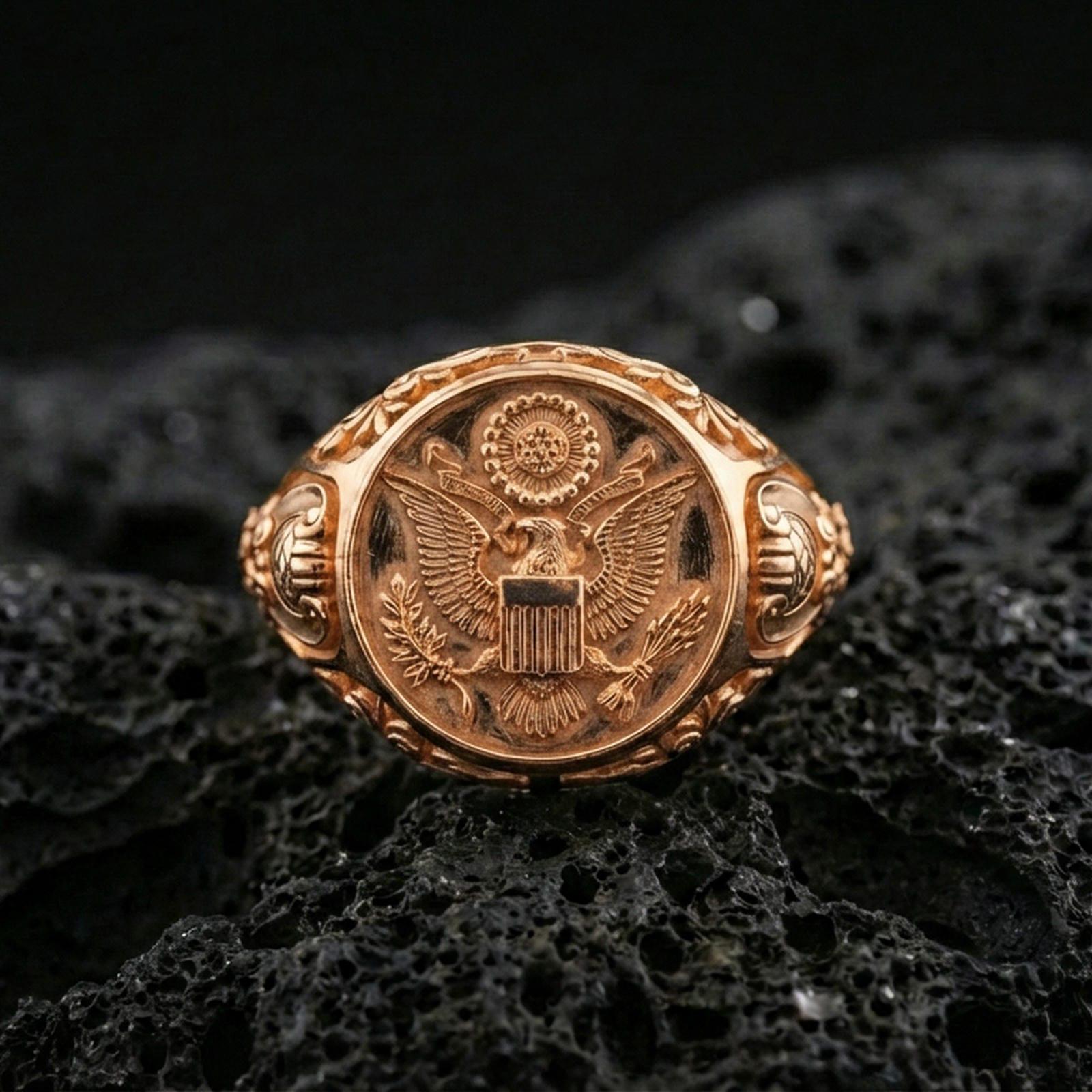 Sterling silver US eagle seal signet ring with a rose gold plated finish, detailed eagle emblem signet face with vintage-style engraving, close-up on volcanic rock