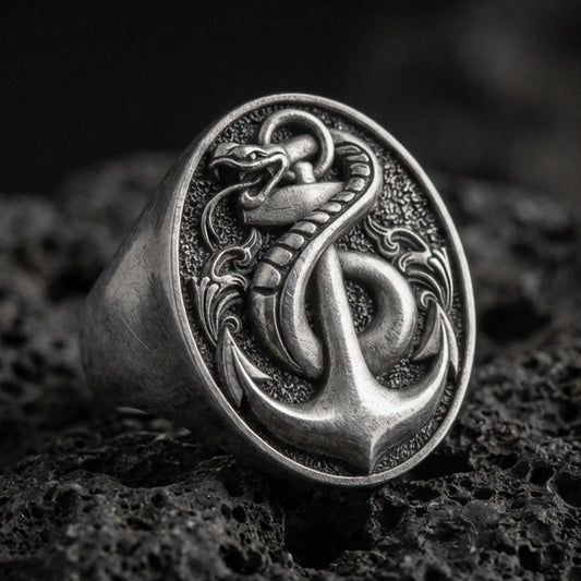 Sterling silver anchor and snake signet ring with an oxidized finish, nautical serpent emblem in high relief, macro on black volcanic rock