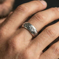 Load image into Gallery viewer, Polished silver floral engraved band ring on finger, crisp flower relief and smooth scrollwork detail, refined everyday wear close-up.
