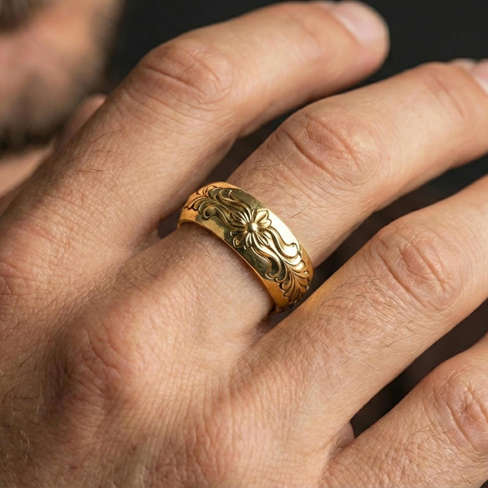 Gold plated floral scroll band worn on finger, detailed flower motif and elegant leaf engraving, premium lifestyle jewelry photo.