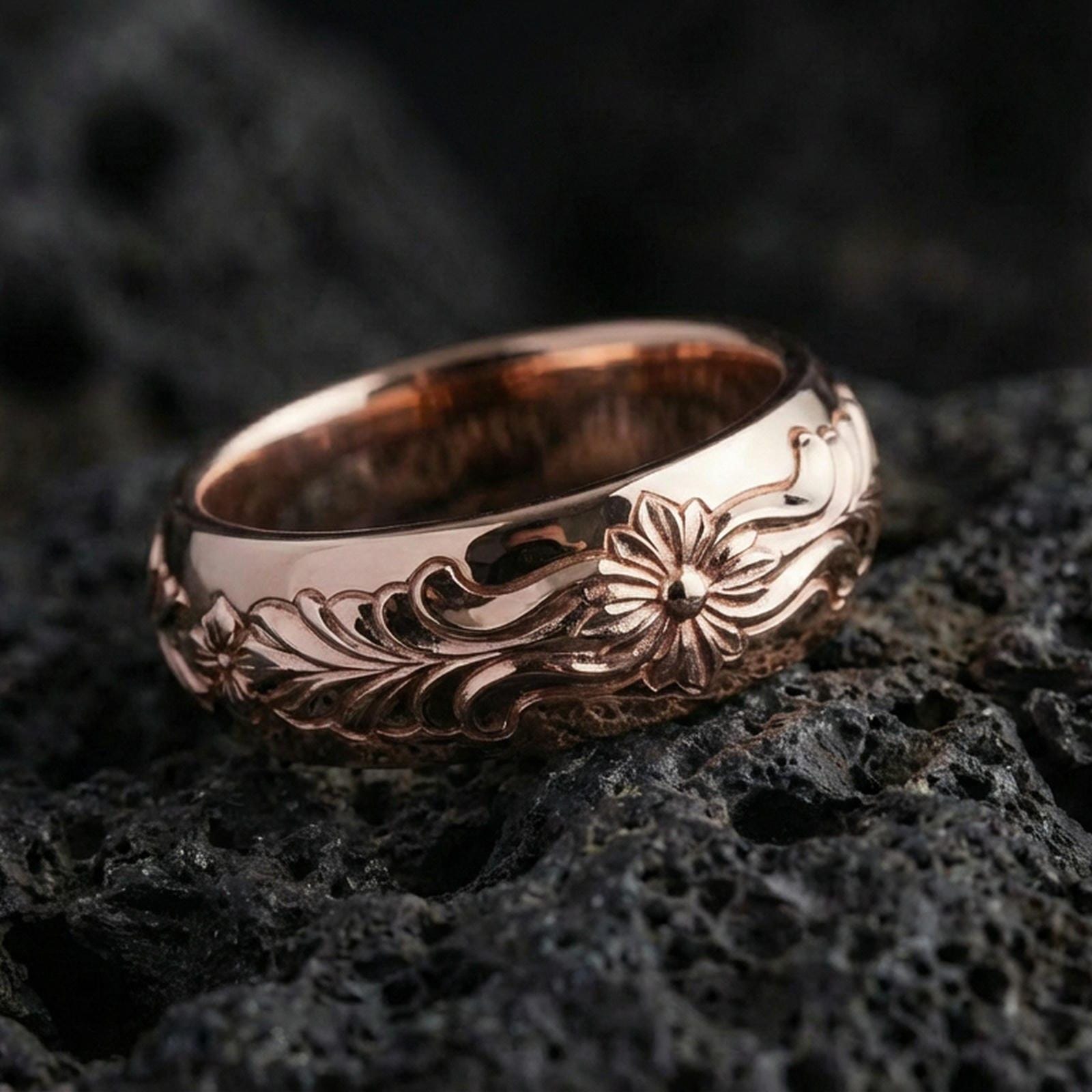 Rose gold plated sterling silver floral pattern band on volcanic stone, ornate flower motif with flowing scroll engraving, minimal high-end close-up.