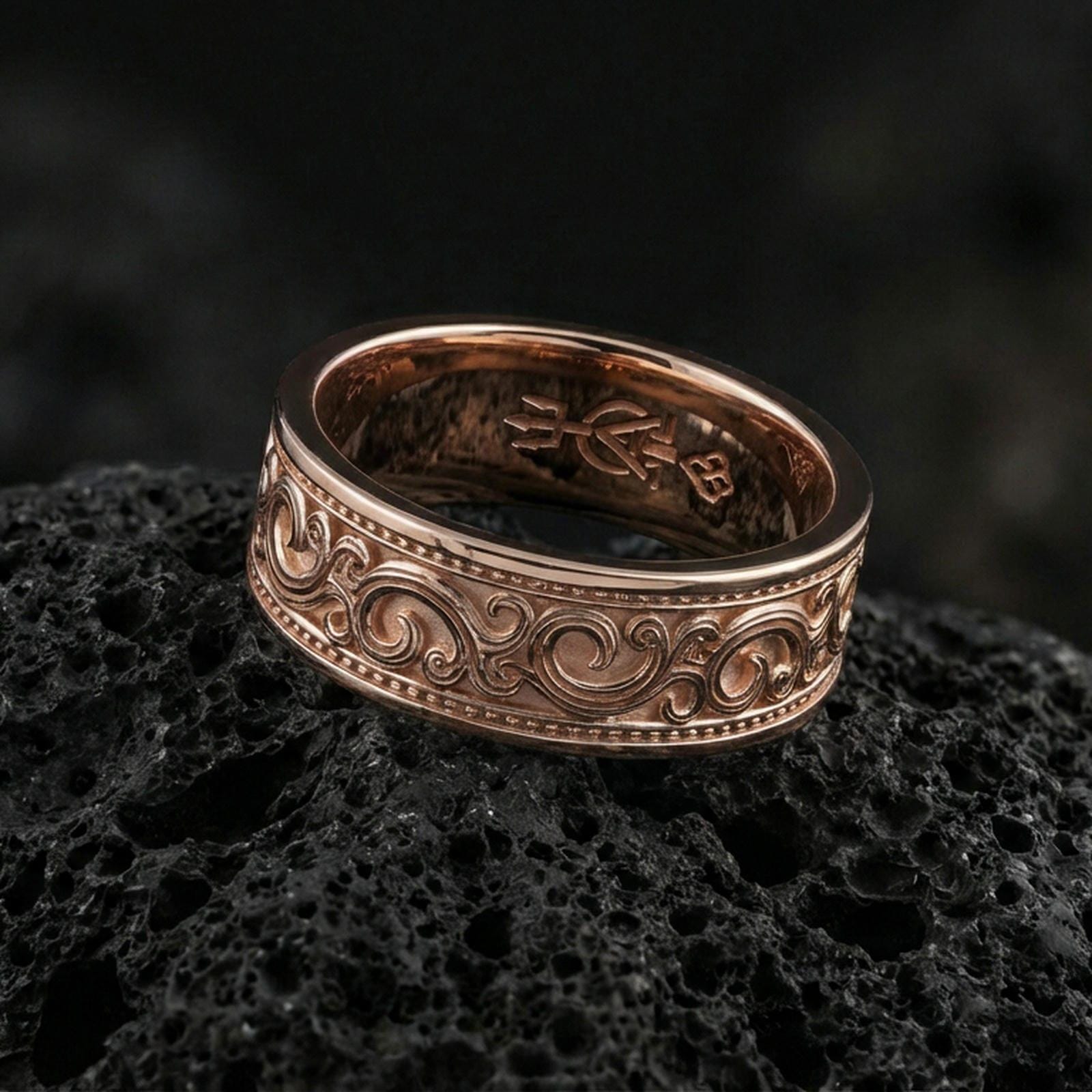 Rose gold plated sterling silver filigree scroll band on volcanic stone, intricate swirl engraving with deep contrast and dotted borders, minimal high-end close-up.