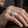 Load image into Gallery viewer, Polished silver oni mask ring on the finger, lifestyle shot focusing on the circular signet face and sculpted horns
