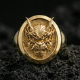 Load image into Gallery viewer, Gold plated oni mask ring on black volcanic rock, detailed view of the dramatic facial relief and sharp contours
