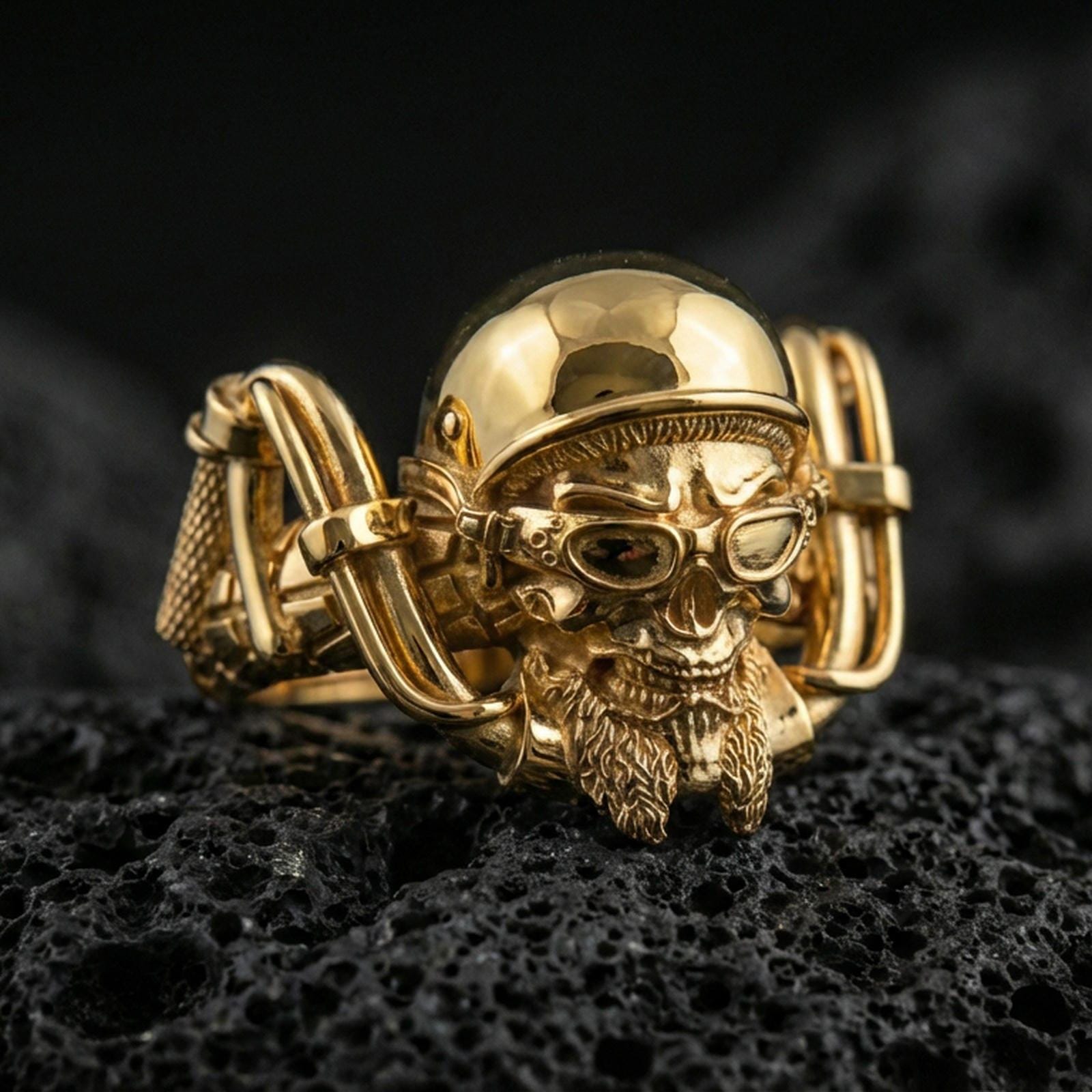 Gold plated biker skull ring on volcanic rock, detailed helmet, goggles, and rugged skull relief, luxury jewelry product photography.