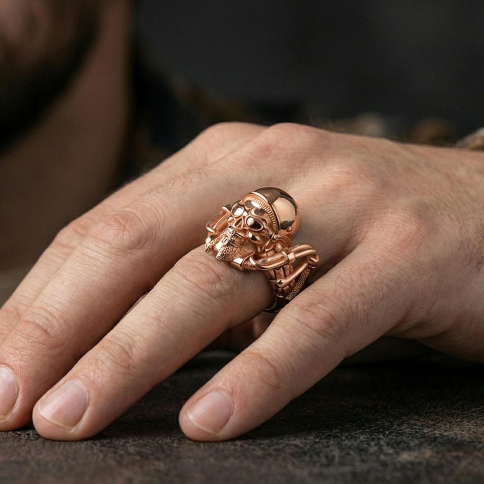 Rose gold plated gothic biker skull ring worn on finger, sculpted helmeted skull relief with beard detail, elegant lifestyle wear shot.