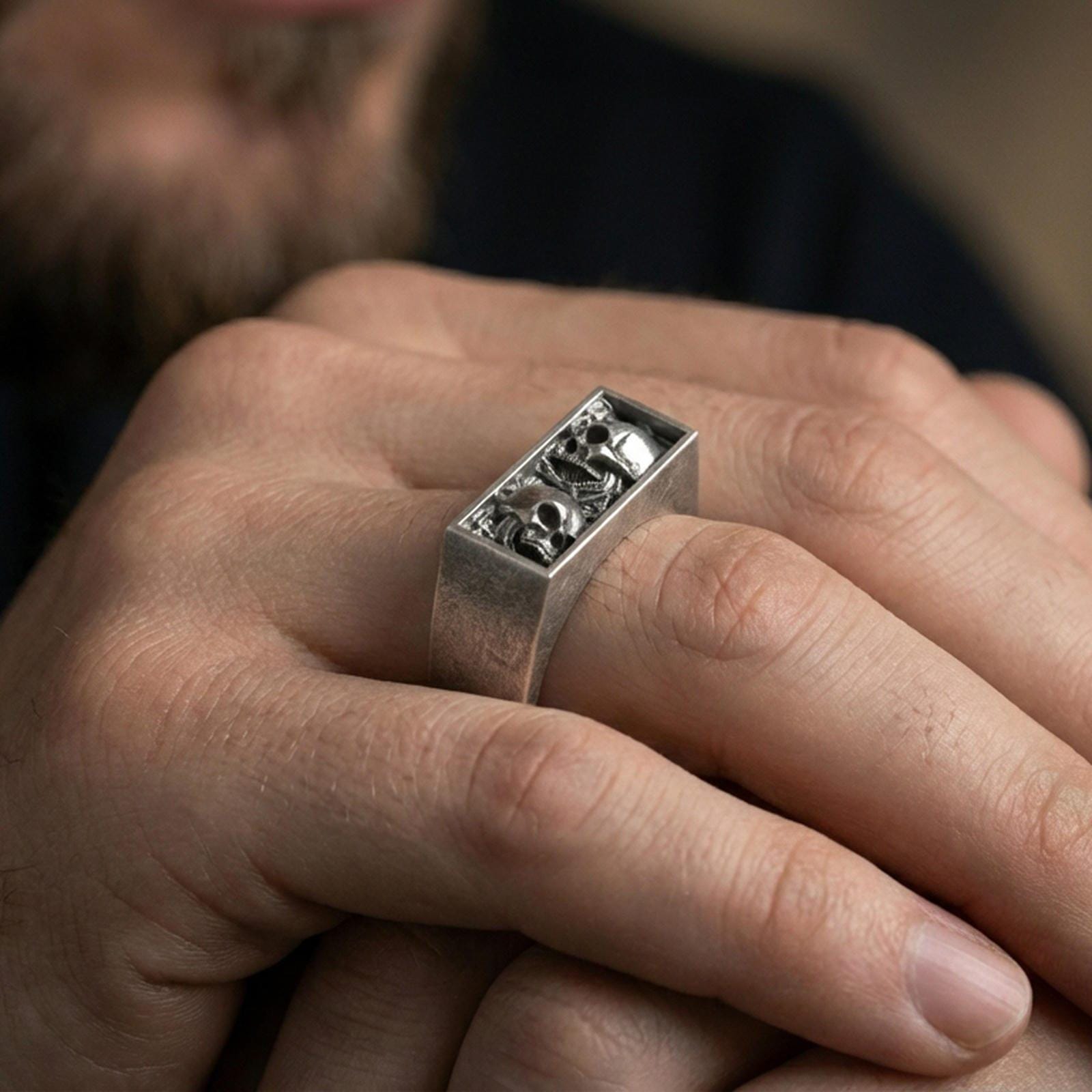 Oxidized finish sterling silver rectangular signet ring worn on a finger, close-up lifestyle shot highlighting the open-window skull detailing