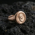 Load image into Gallery viewer, Sterling silver Roman coin signet ring with a rose gold plated finish, classical emperor portrait medallion and ringed border texture, close-up on volcanic rock
