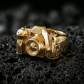 Load image into Gallery viewer, Sterling silver camera signet ring with a gold plated finish, detailed 3D camera motif with textured lens barrel, macro on volcanic rock
