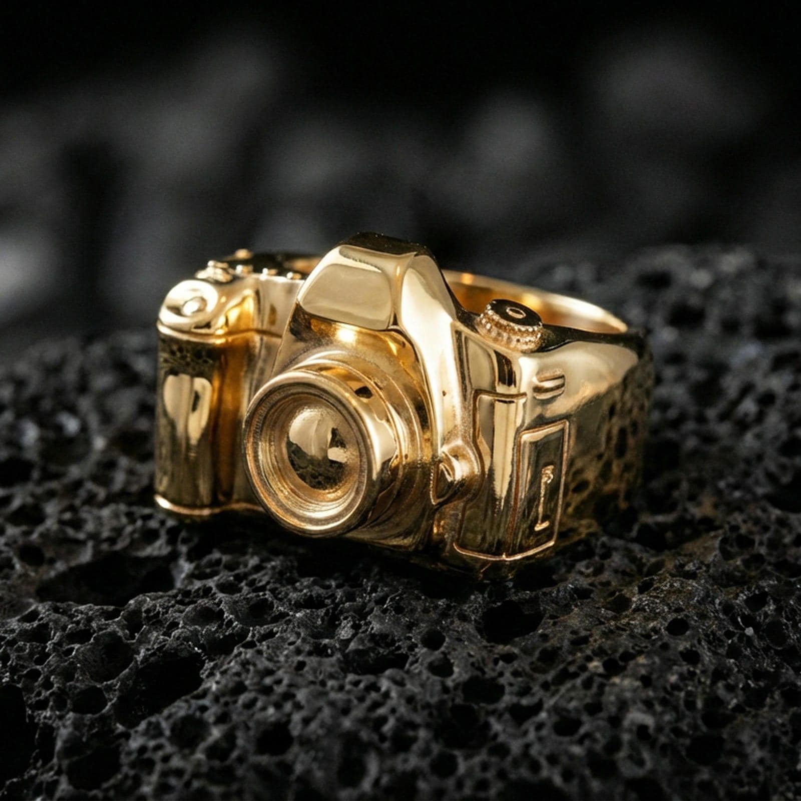 Sterling silver camera signet ring with a gold plated finish, detailed 3D camera motif with textured lens barrel, macro on volcanic rock
