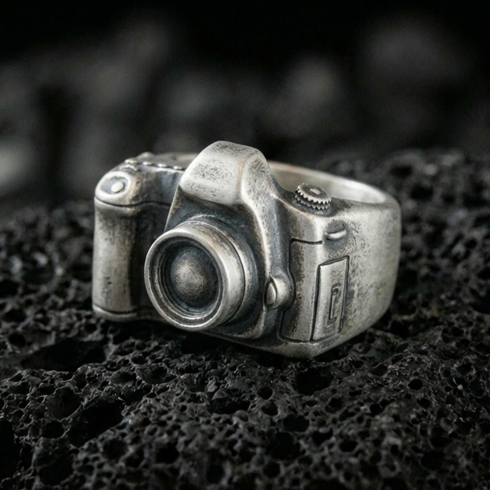 Sterling silver camera signet ring with an oxidized finish, 3D vintage camera design with lens detail, macro on black volcanic rock