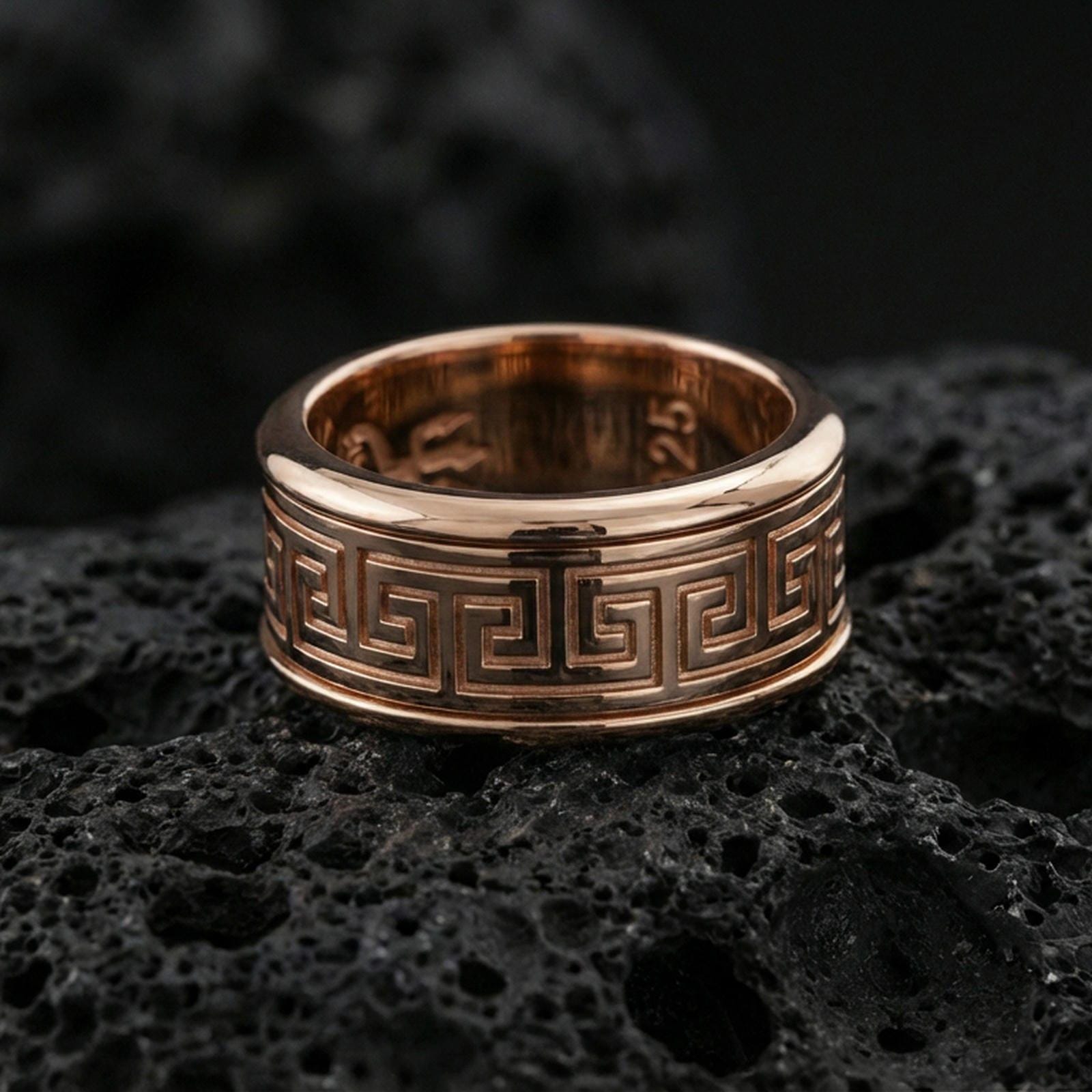 Rose gold plated sterling silver Greek key band on volcanic stone, sharp geometric meander engraving with refined edges, minimal high-end close-up.
