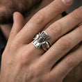 Load image into Gallery viewer, Oxidized sterling silver crucifix Jesus ring worn on finger, raised Christ relief and open cross frame detail, natural lifestyle hand shot with shallow depth of field.
