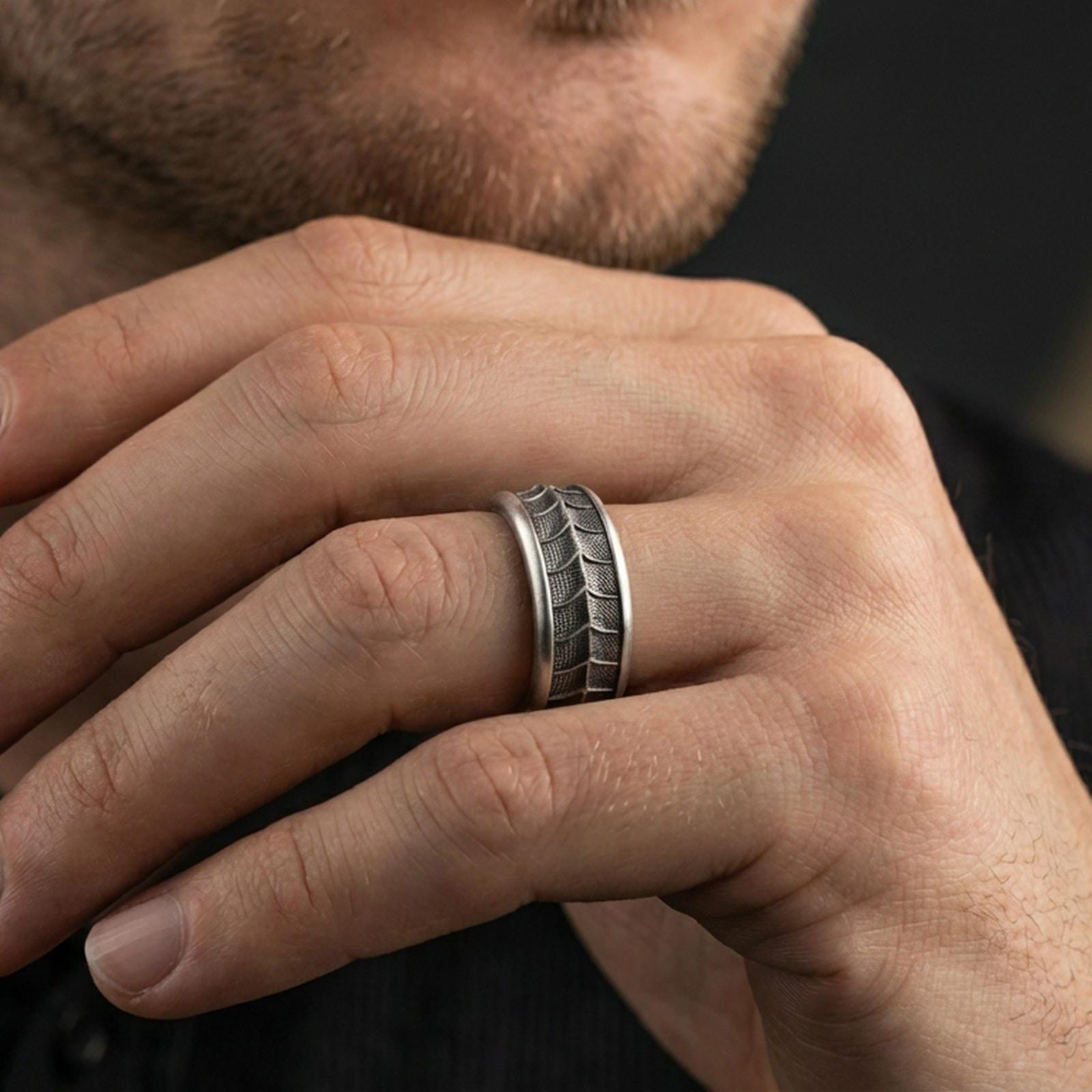 Oxidized sterling silver lizard scale spinner band worn on finger, textured reptile pattern detail on rotating center, natural lifestyle hand shot with shallow depth of field.