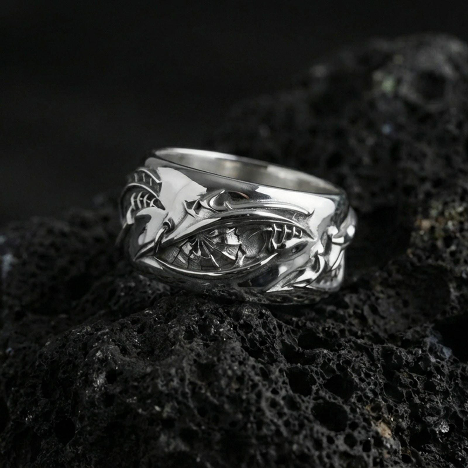 Polished silver nature-inspired roots band ring on black volcanic stone, crisp twisted vine relief with textured interior detail, centered close-up studio lighting.