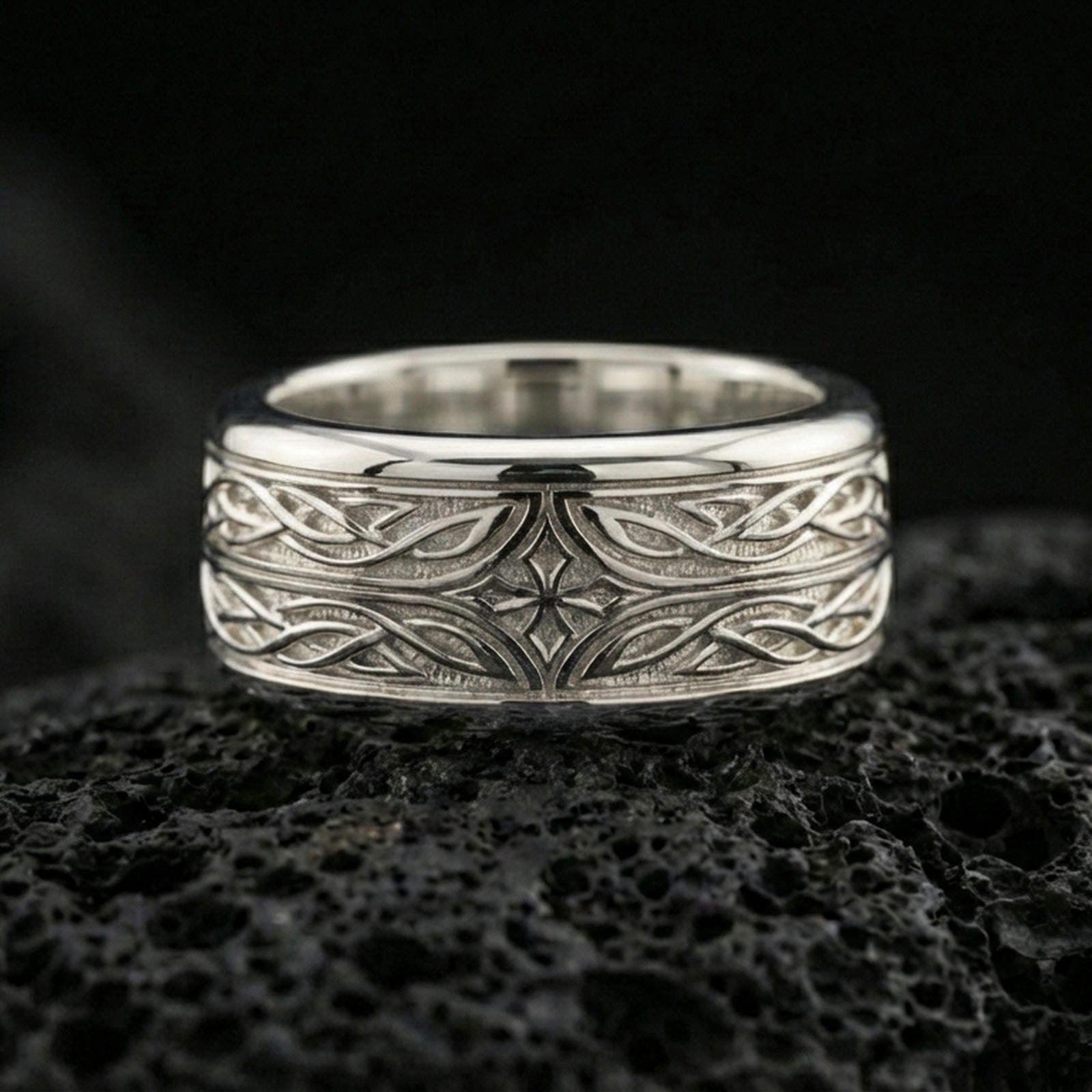 Polished silver elven star fidget spinner ring on black volcanic stone, crisp intertwined knot pattern with central star detail, centered close-up studio lighting.