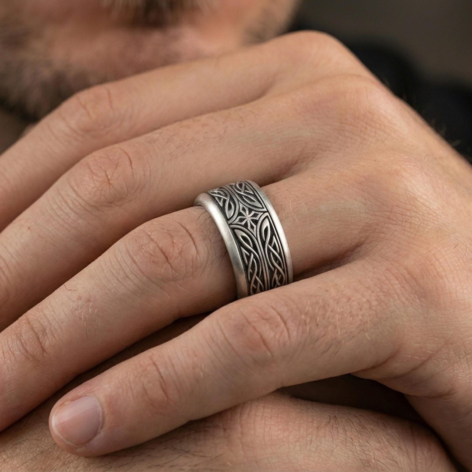 Oxidized sterling silver elven star spinner band worn on finger, Celtic knotwork and star motif detail on rotating center, natural lifestyle hand shot with shallow depth of field.
