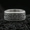 Load image into Gallery viewer, Oxidized sterling silver elven star spinner band ring on dark volcanic rock, Celtic knotwork and star motif on rotating center, premium macro product shot.
