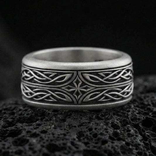 Oxidized sterling silver elven star spinner band ring on dark volcanic rock, Celtic knotwork and star motif on rotating center, premium macro product shot.