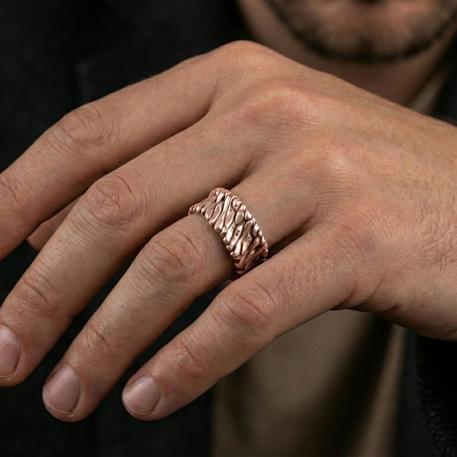 Rose gold plated twisted rope band ring worn on finger, sculpted spiral texture detail, elegant lifestyle wear shot.