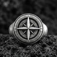 Load image into Gallery viewer, Sterling silver compass rose signet ring with an oxidized finish, engraved cardinal directions and nautical star design, macro on black volcanic rock
