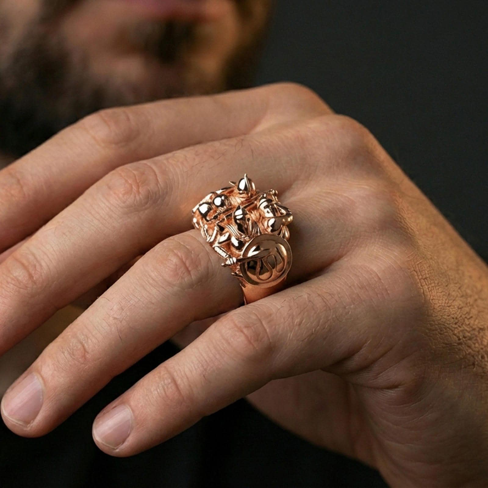 Sterling silver hoplite warrior statement ring on a finger, macro lifestyle shot featuring the rose gold plated finish and intricate shield-and-sword battle motif