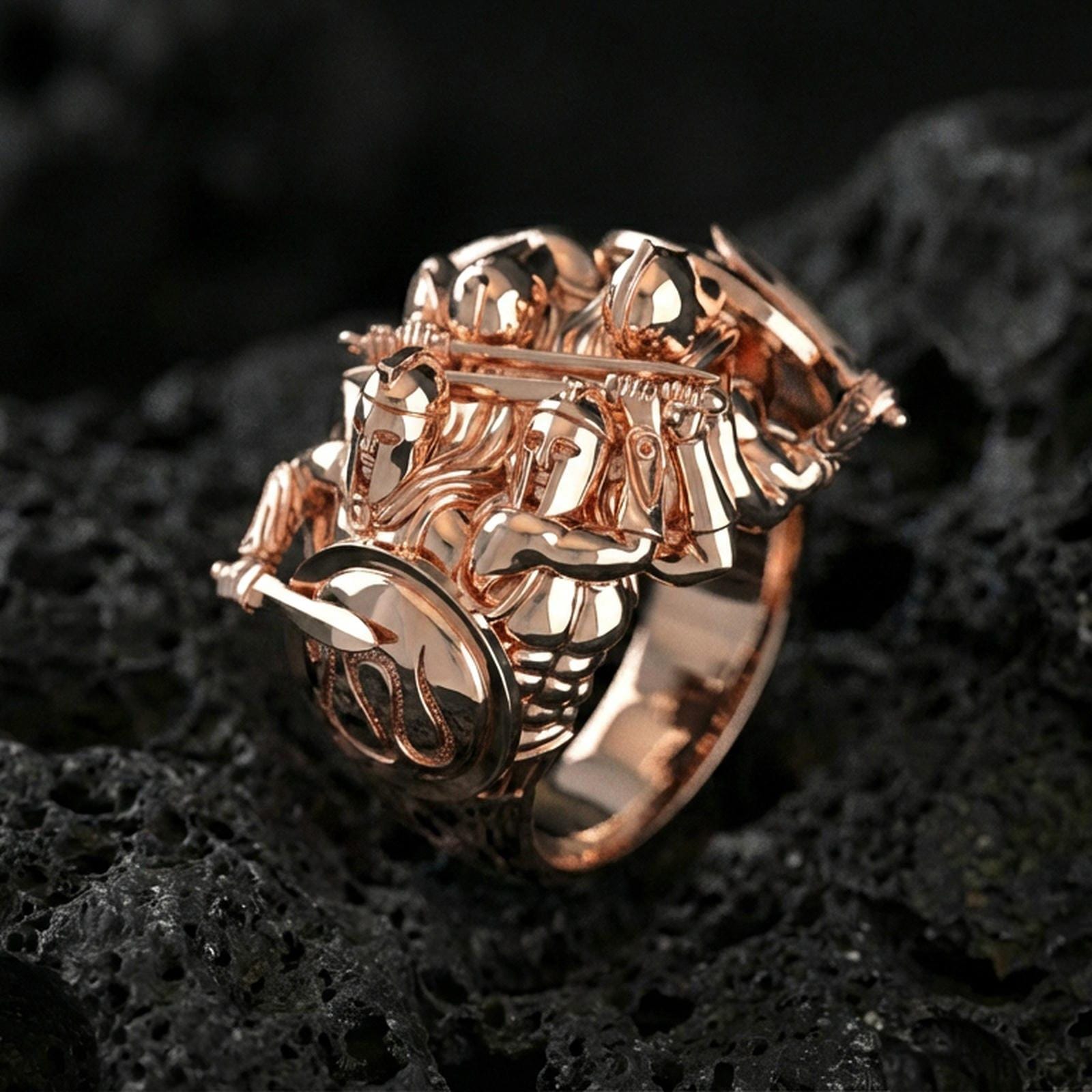 Sterling silver warrior sculpture ring with a rose gold plated finish, dramatic Greek soldier combat design with shield and blade details, close-up on black volcanic rock