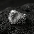 Load image into Gallery viewer, Sterling silver pharaoh head signet ring in a polished silver finish, oval statement face with ancient Egyptian-inspired relief and decorative band carving, close-up on volcanic stone
