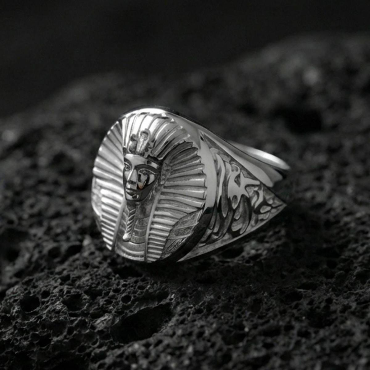 Sterling silver pharaoh head signet ring in a polished silver finish, oval statement face with ancient Egyptian-inspired relief and decorative band carving, close-up on volcanic stone