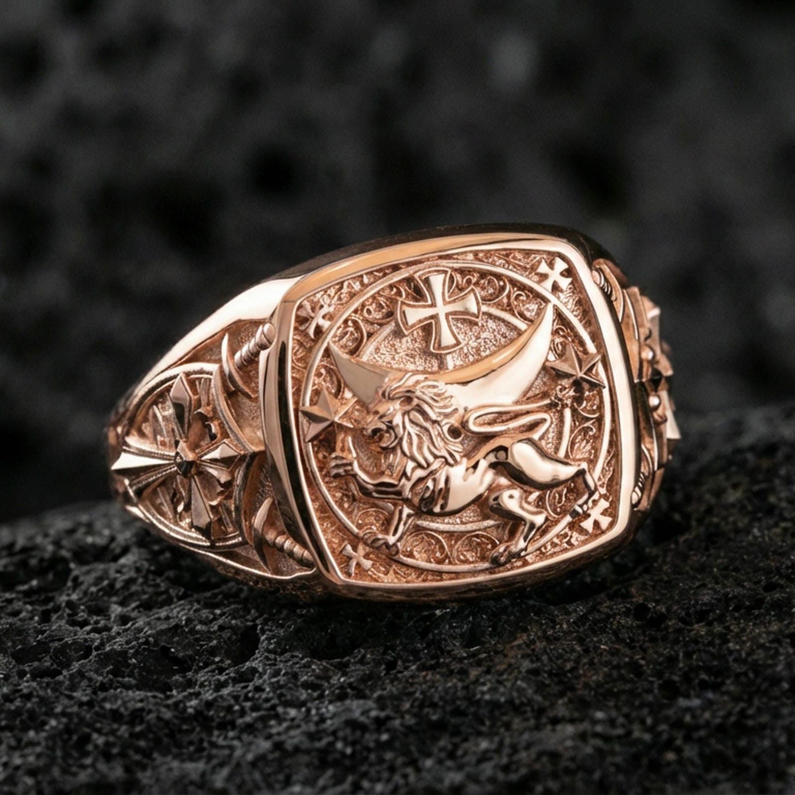 Sterling silver medieval heraldry ring with a rose gold plated finish, detailed Lion of Judah emblem and cross accents on a square signet face, close-up on black volcanic rock