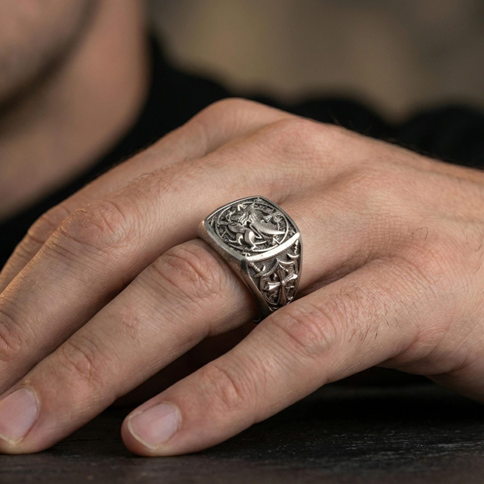 Sterling silver Lion of Judah signet ring worn on a finger, close-up lifestyle shot highlighting the oxidized square face and heraldic lion with cross motif