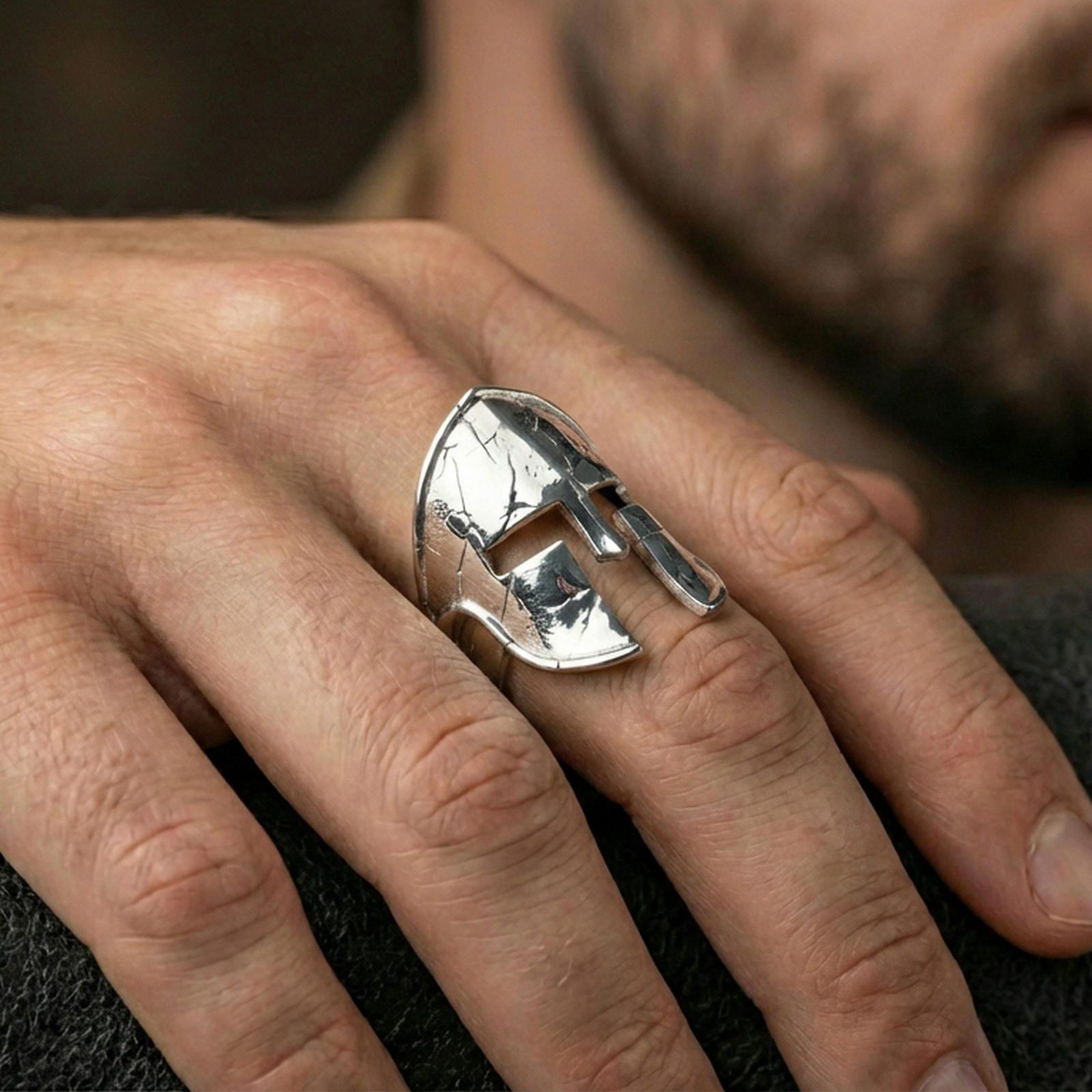 Sterling silver Spartan helmet statement ring on a finger, macro lifestyle image emphasizing the polished silver finish and sculptural warrior helmet face