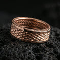 Load image into Gallery viewer, Rose gold plated sterling silver braided rope band on volcanic stone, sculpted woven texture with deep contrast and dotted edges, minimal high-end close-up.
