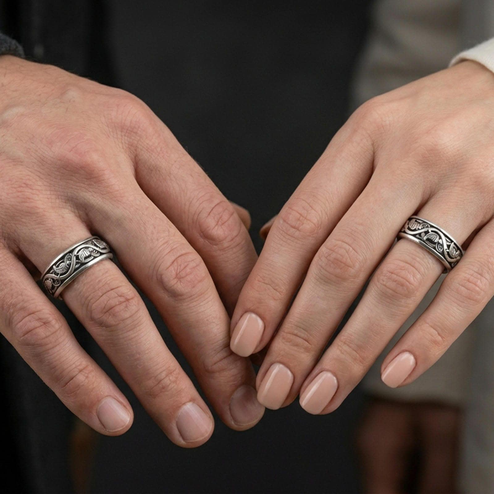 Oxidized sterling silver dove pattern band worn on finger, repeating bird motif and scrollwork detail, natural lifestyle hand shot with shallow depth of field.