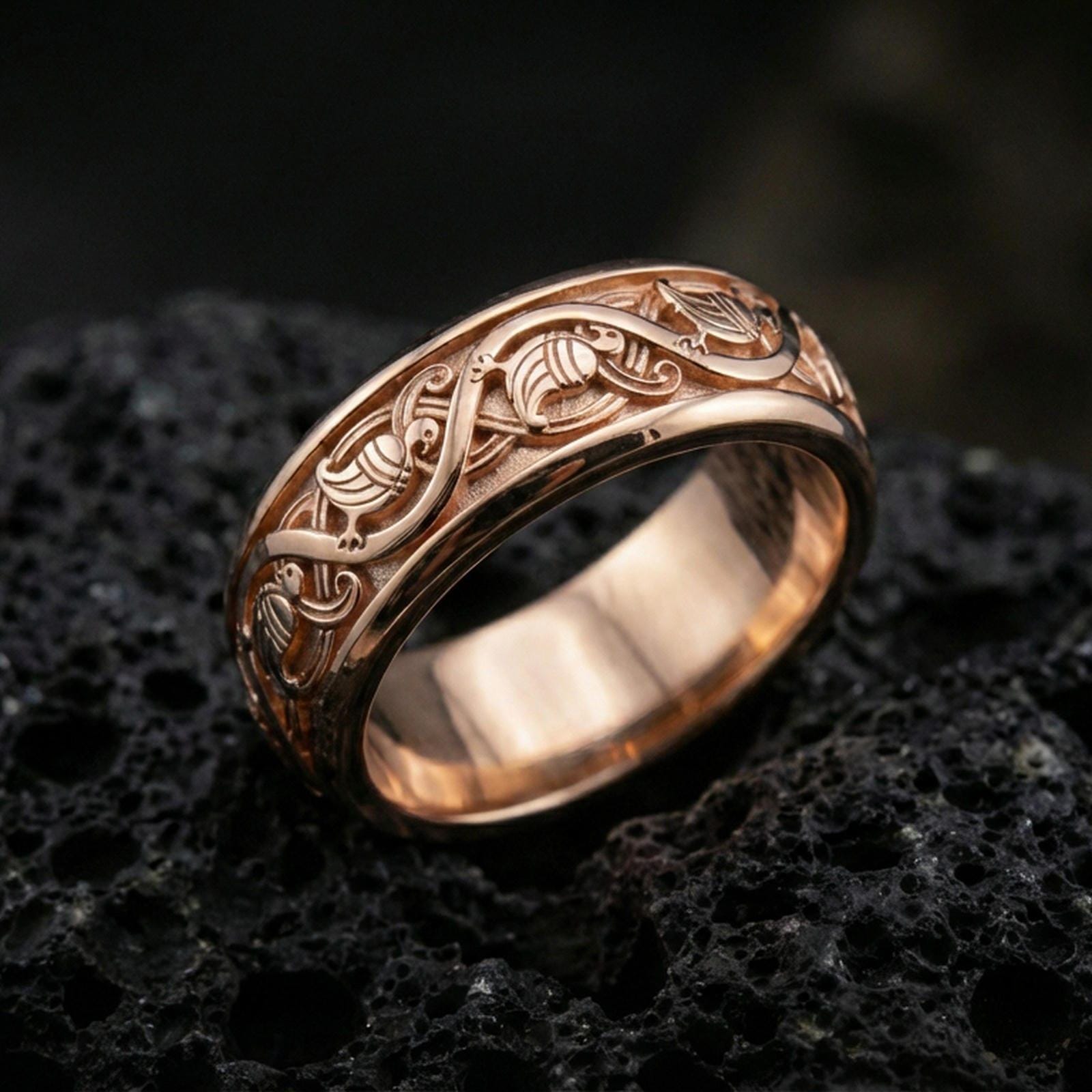 Rose gold plated sterling silver dove band on volcanic stone, intricate bird motif engraving with deep contrast and smooth edges, minimal high-end close-up.