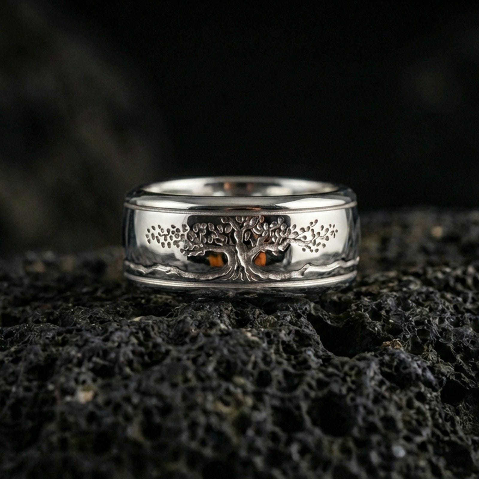 Polished silver Yggdrasil fidget spinner ring on black volcanic stone, crisp tree of life engraving with smooth comfort edges, centered close-up studio lighting.