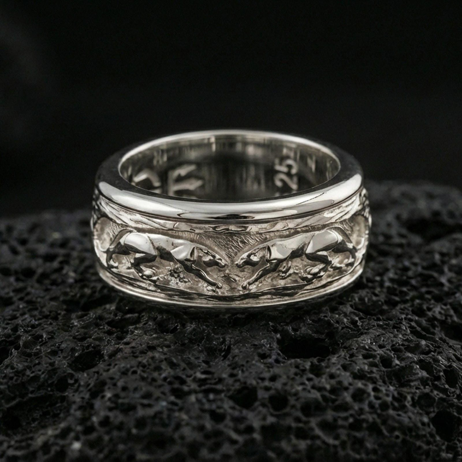 Polished silver jaguar fidget spinner ring on black volcanic stone, crisp big cat relief scene on rotating band, centered close-up studio lighting.