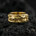 Load image into Gallery viewer, Gold plated Michelangelo Moses spinner band ring on volcanic rock, detailed portrait relief on rotating band with vintage scroll accents, luxury jewelry product photography.
