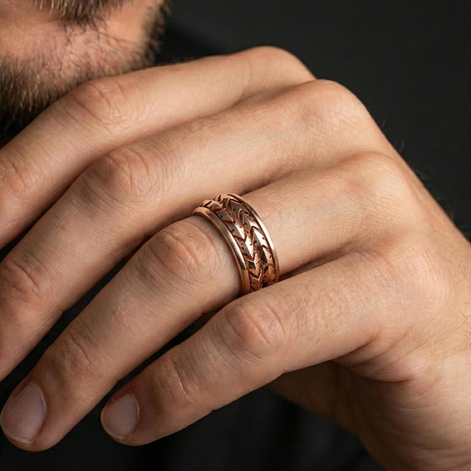 Rose gold plated arrowhead spinner ring worn on finger, bold geometric arrow relief detail, elegant lifestyle wear shot.