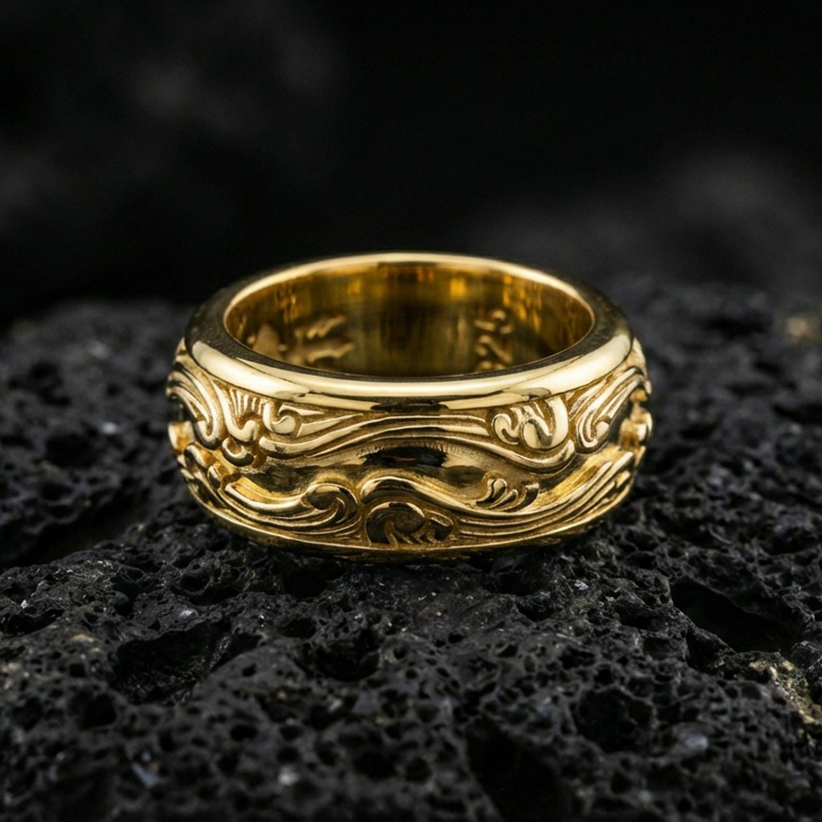 Gold plated scrollwave spinner band ring on volcanic rock, detailed flowing wave filigree on rotating band, luxury jewelry product photography.