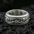 Load image into Gallery viewer, Oxidized sterling silver scrollwave spinner band ring on dark volcanic rock, flowing wave filigree engraving on rotating center, premium macro product shot.
