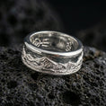 Load image into Gallery viewer, Polished silver mountain landscape band ring on black volcanic stone, crisp peak skyline engraving with brushed finish, centered close-up studio lighting.
