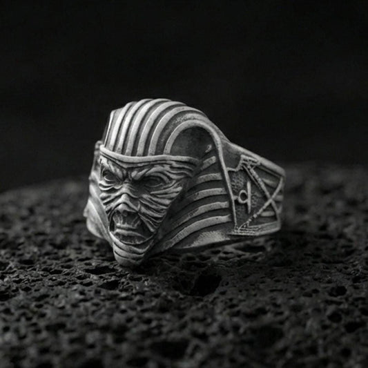Sterling silver mummy pharaoh mask ring with an oxidized finish, horror-inspired Egyptian face design with ribbed headdress detail, macro on black volcanic rock