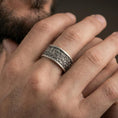Load image into Gallery viewer, Oxidized sterling silver jungle wildlife band worn on finger, detailed foliage relief and animal engraving, natural lifestyle hand shot with shallow depth of field.
