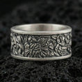 Load image into Gallery viewer, Oxidized sterling silver jungle wildlife band ring on dark volcanic rock, high-relief leaves and exotic animal engraving, premium macro product shot.
