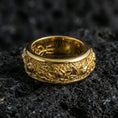 Load image into Gallery viewer, Gold plated lotus spinner band ring on volcanic rock, detailed lotus flower relief on rotating band with ornamental scroll accents, luxury jewelry product photography.
