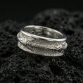 Load image into Gallery viewer, Polished silver arrow fidget spinner ring on black volcanic stone, crisp arrowhead and wire-wrapped shaft detail with rugged texture, centered close-up studio lighting.

